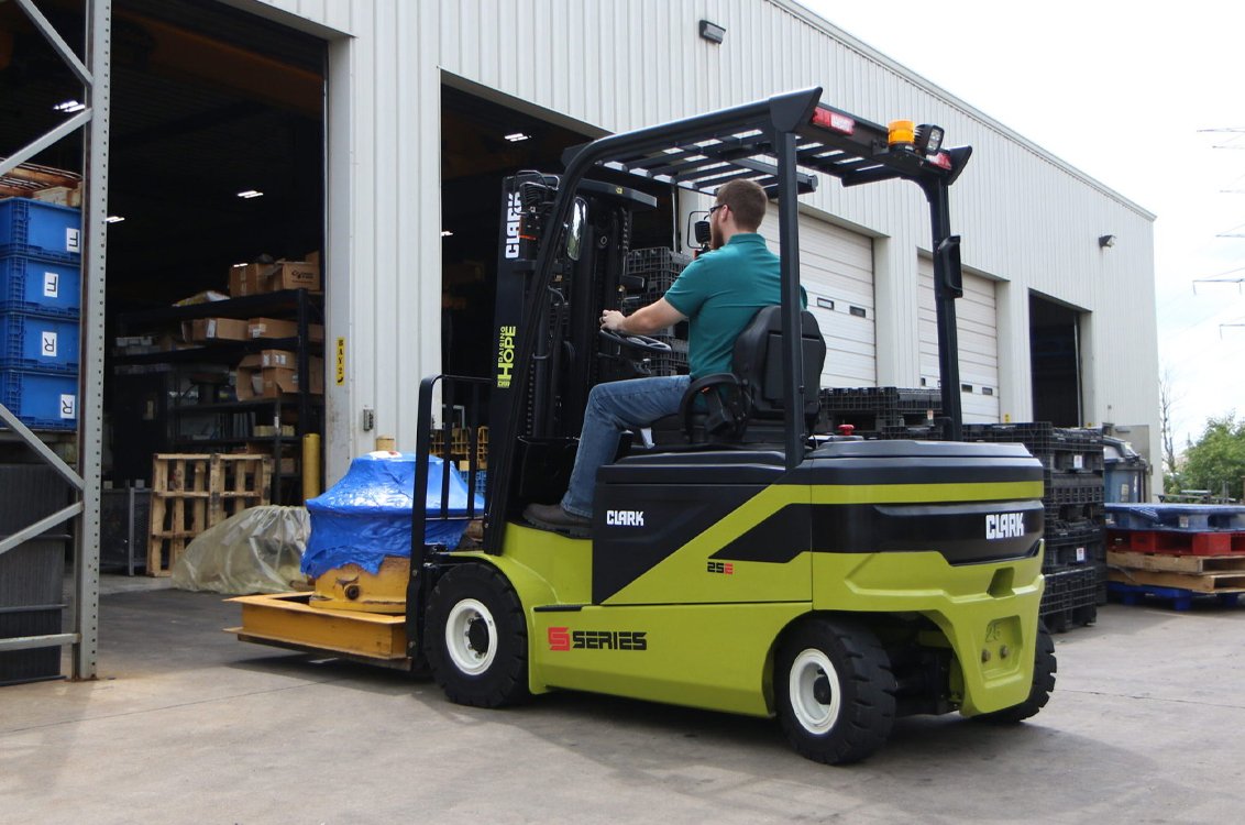 Clark SE25 Electric Rider Pneumatic Forklift driving into a warehouse