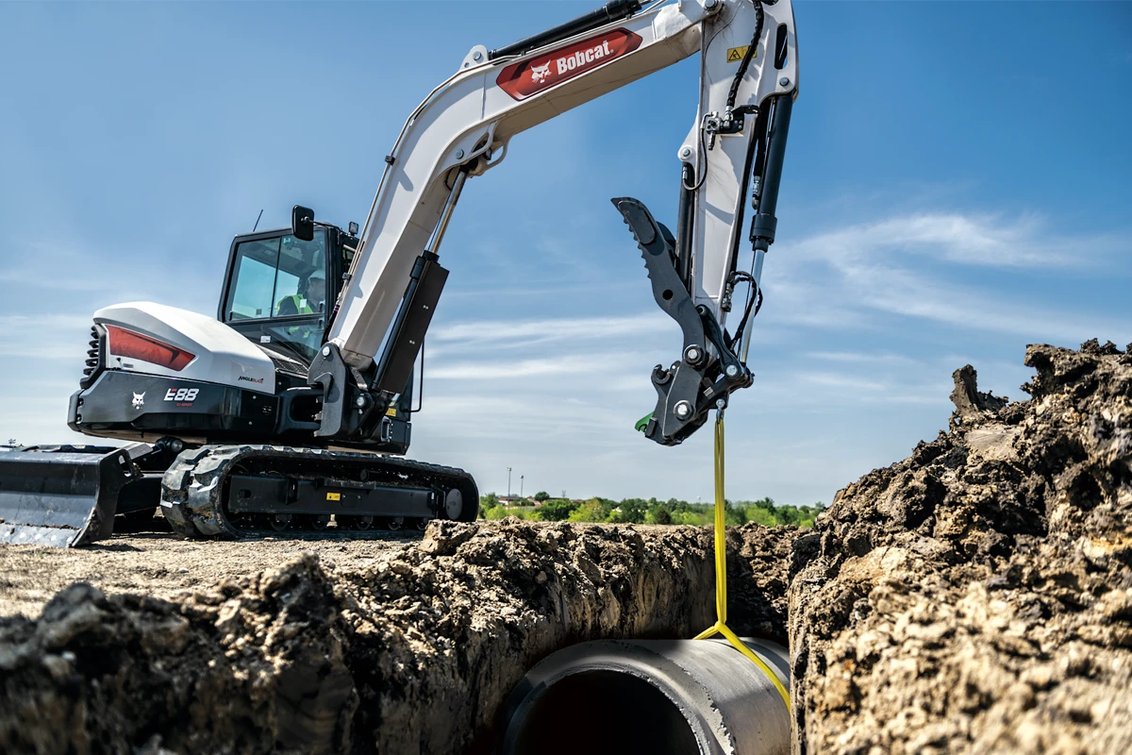 Bobcat E88 Mini Excavator dropping pipe into trench