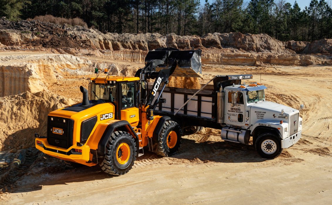 JCB 437 Wheel Loader releasing a load of dirt into dump truck