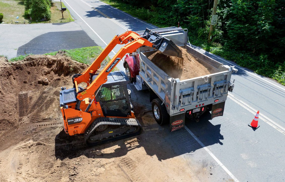 DEVELON DTL30 Compact Track Loader dumping a load of dirt into a truck