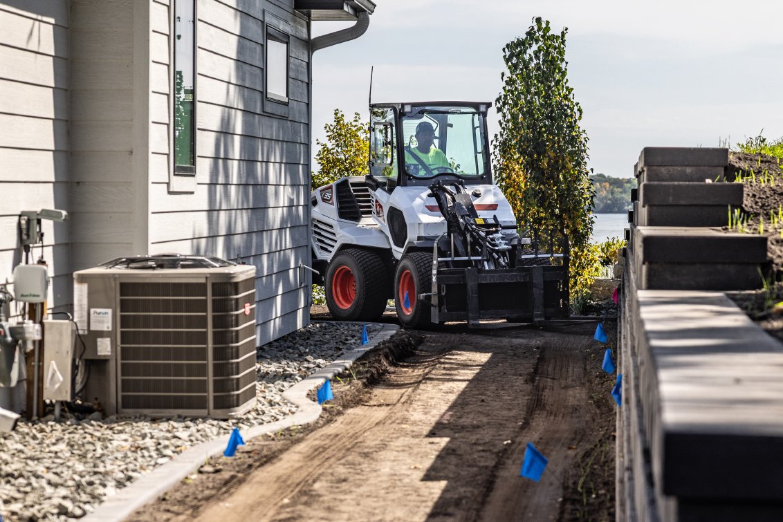 Bobcat L35 Small Articulated Loader with pallet fork attachment in tight work area