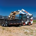 Bobcat S86 Skid Steer dumping rocks into trailer