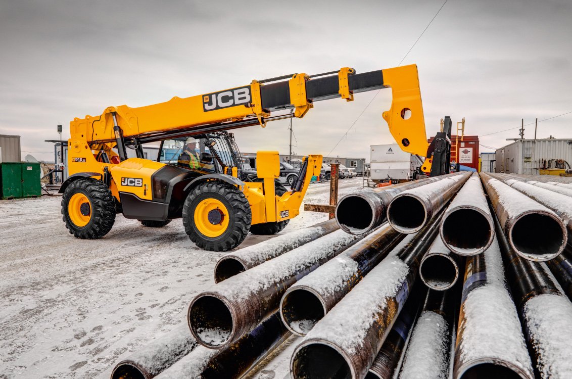 JCB 512-56 Telehandler hauling an awkward and heavy load of pipes on a construction site