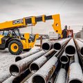 JCB 512-56 Telehandler hauling an awkward and heavy load of pipes on a construction site