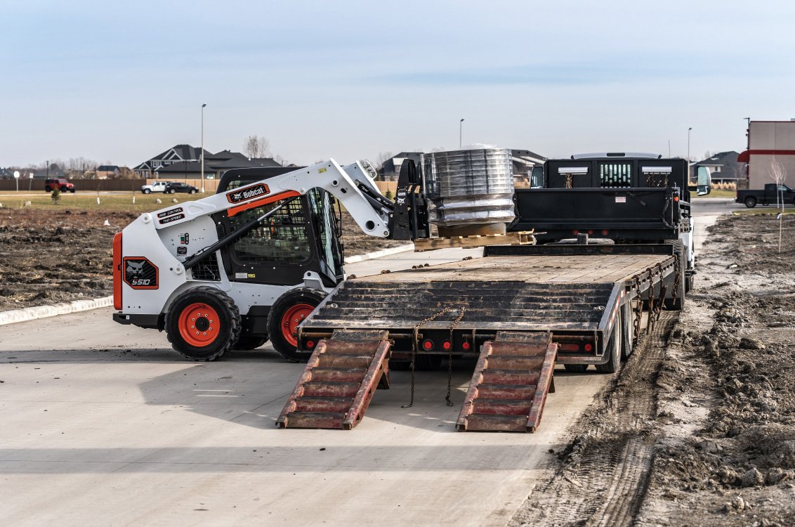 Bobcat S510 Skid Steer Loader loading flat deck trailer
