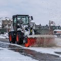 Bobcat L95 Compact Wheel Loader sweeping snow & dirt off a street