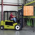 Clark GEX50 Electric Rider Pneumatic Forklift loading a large heavy box on the rack