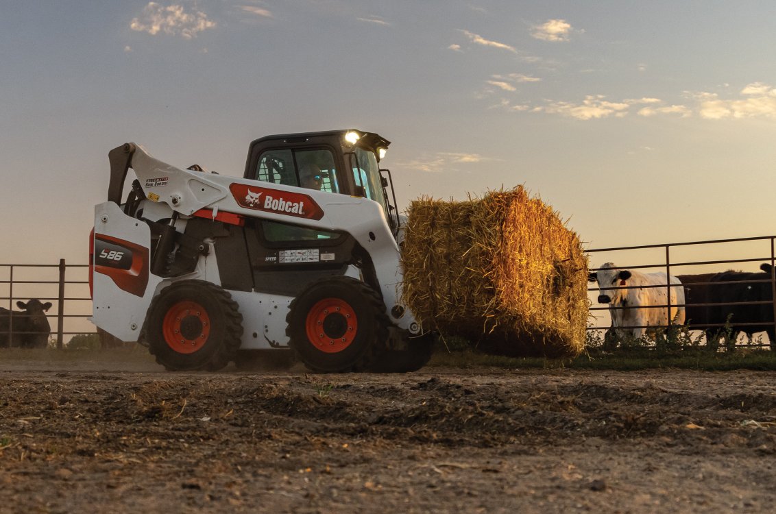 Bobcat S86 Skid Steer hauling a bale of hay